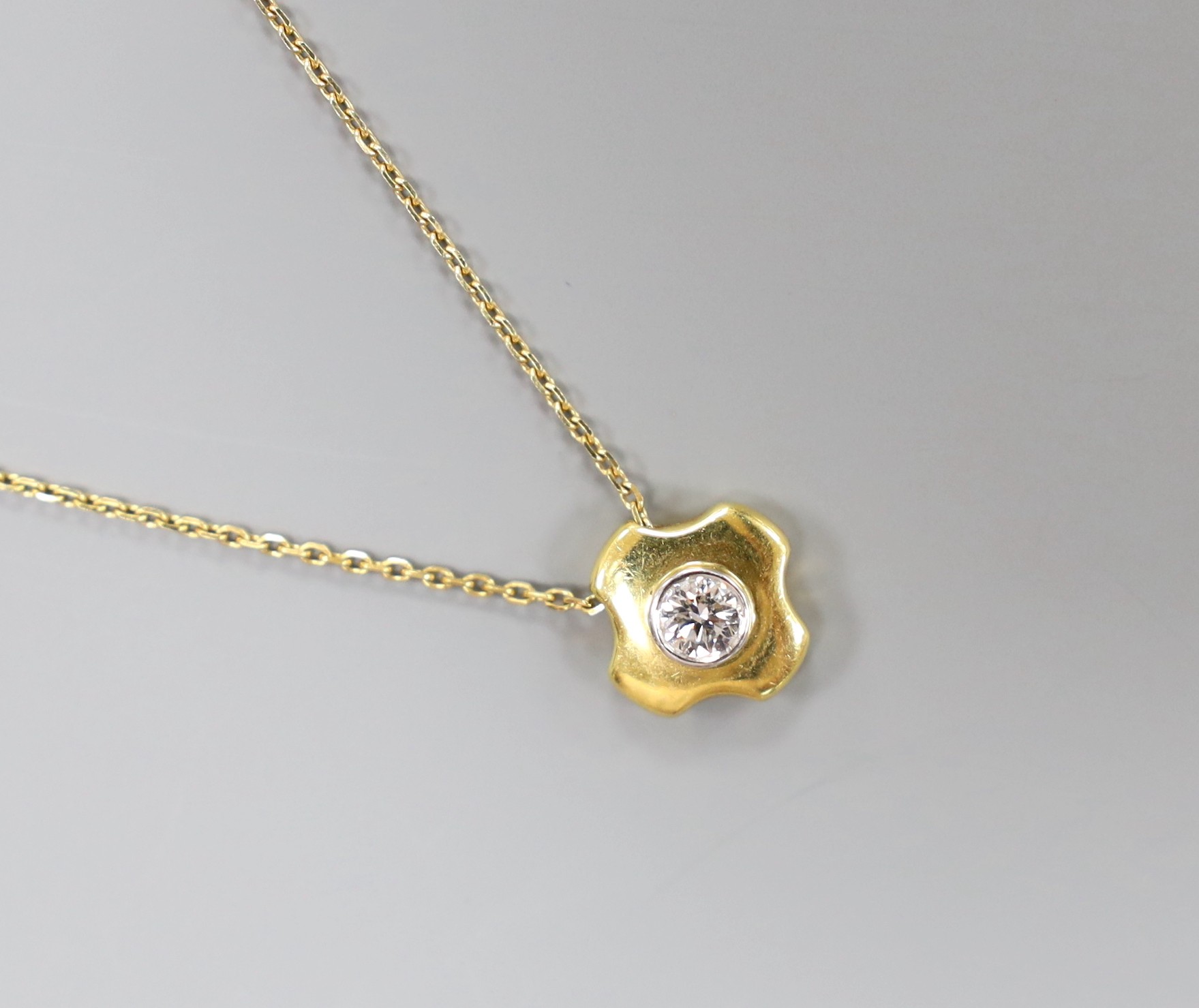 A modern 18ct gold and single stone diamond set quatrefoil pendant, 7mm, on an 18ct gold fine link chain, 38cm, gross weight 6 grams